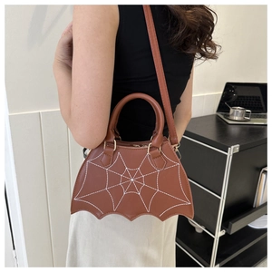 Detailed view of brown leather bat-shaped handbag with white spiderweb embroidery pattern