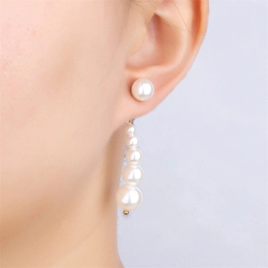 Detail of model wearing long white pearl drop earrings with elegant gradient design