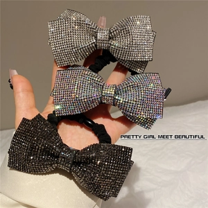 Close-up of three rhinestone bow hair ties in silver, colorful, and black finishes