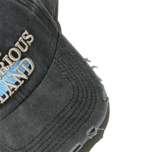 Detail of distressed brim with frayed edges and 3D embroidery on washed cotton cap