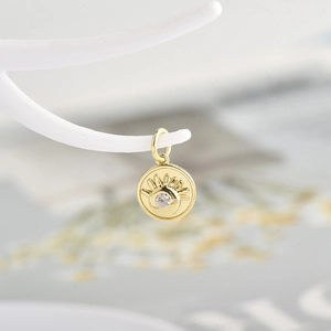 Macro detail of gold-plated evil eye pendant with center white zircon on white display