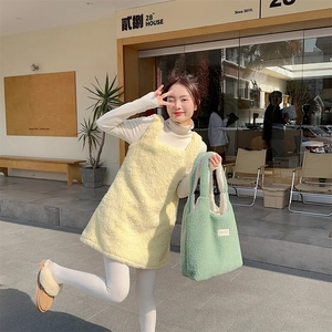 Close-up of green plush tote bag paired with yellow fleece dress in outdoor cafe setting