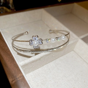 Gros plan d'un bracelet ouvert double rang avec trèfle en perles et pavé de oxydes de zirconium