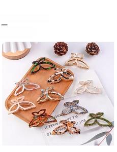 Flat lay of multiple butterfly hair claws in marble and leopard prints on a wooden tray