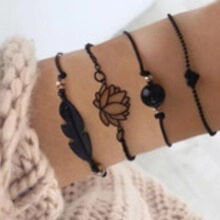 Vierteiliges schwarzes Armband-Set mit Feder-, Lotus- und Herzanhängern am Handgelenk