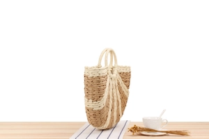 Detail of a semi-circular woven handbag with beige and brown striped paper rope texture