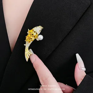 Spilla carpa koi dorata con zircone giallo e perla su un abito nero a righe elegante