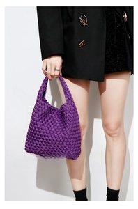 Detail of purple woven bucket bag with wide silk-texture straps on a black blazer