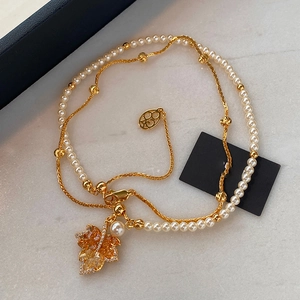 Macro shot of maple leaf pendant with amber zircons and elegant pearl chain details