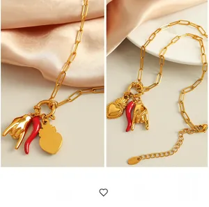 Detail of gold chain necklace with rock sign, red chili, and heart pendants on silk