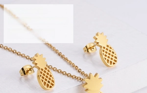 Detailed macro view of gold-plated pineapple jewelry set including earrings and pendant necklace