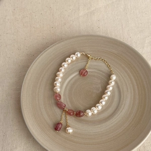 Detailed view of Baroque pearls and pink gemstones with a gold chain on a ceramic plate