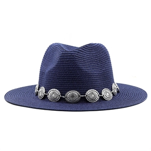 Detailed view of dark blue woven straw fedora hat with bohemian silver sunburst metal band