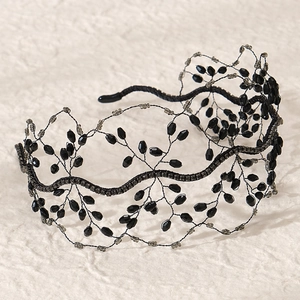 Dettaglio del cerchietto vintage con perline di cristallo nero e trama a rete su carta beige