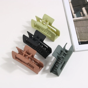 Top view of four large matte rectangle hair claws in olive, black, brown, and charcoal