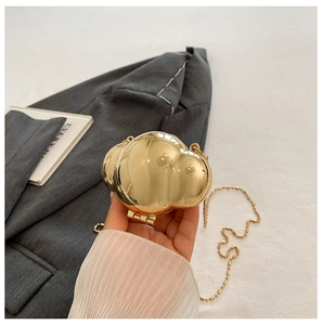 Close-up of a mini gold cloud-shaped metal shell bag with a fine chain strap