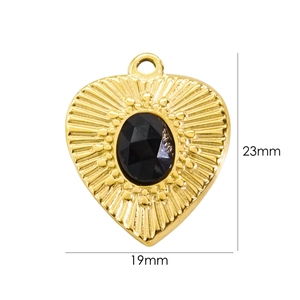 Macro detail of a 23mm x 19mm gold heart pendant featuring a black oval natural stone inlay
