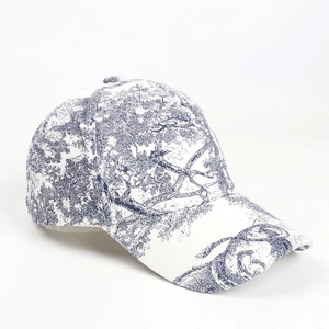 Detail of blue Toile de Jouy landscape print on a classic white six-panel baseball cap