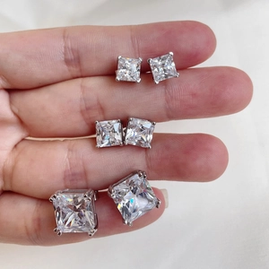Three sizes of silver square-cut studs with clear cubic zirconia held between fingers