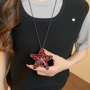 Close-up of leopard print star pendant with fine stitching on a black cord necklace
