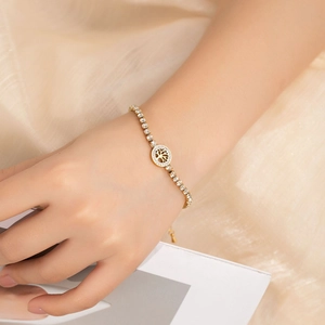 Close-up of a gold tree of life bracelet with white crystals worn on a wrist