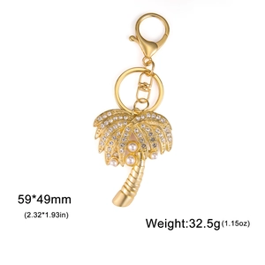 Porte-clés palmier doré orné de strass et perles blanches sur un fond blanc pur