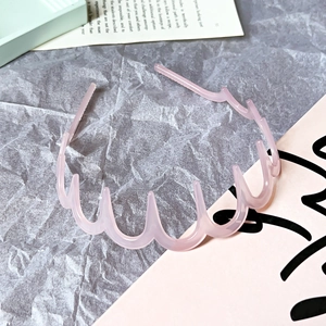 Detailed view of a pink wavy headband with non-slip teeth on a stylish background