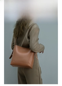 Close-up of caramel brown leather bucket bag showing reinforced stitching and texture