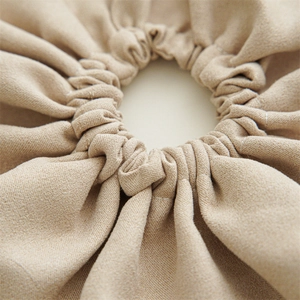 Detailed macro view of beige cotton linen fabric texture and pleats on oversized scrunchie