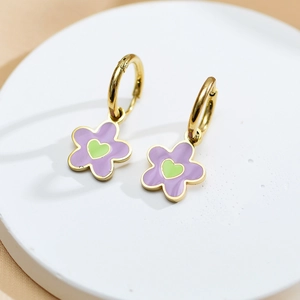 Macro detail of gold-plated flower hoop earrings with purple petals and green heart