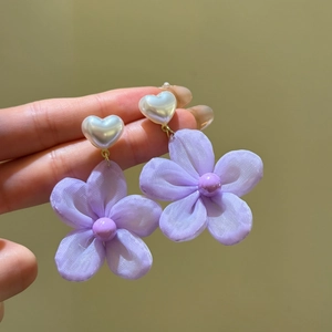 Detail showing purple fabric flower earrings with white heart-shaped pearl studs