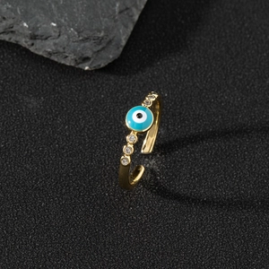 Macro shot of gold evil eye open ring with blue enamel and zircons on black stone