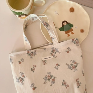 Detailed close-up of floral cotton tote bag with 'simple wish' label and smooth zipper