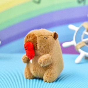 Macro detail of a cute brown plush capybara keychain holding a red balloon ornament
