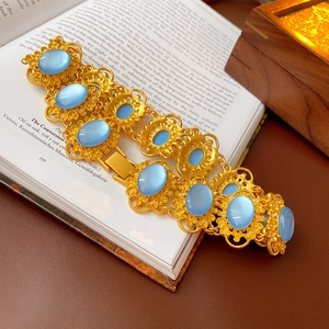 Close-up of vintage gold necklace with oval blue gemstones resting on a book