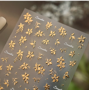 Detailed macro view of 3D embossed gold floral nail art stickers with metallic texture