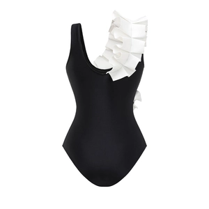 Detail of one-shoulder black swimsuit featuring a contrasting white ruffled sleeve design