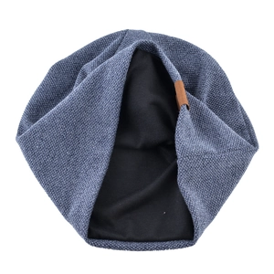 Detail of blue knitted beanie with soft black lining and brown leather patch accent