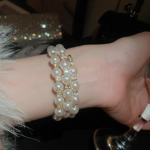 Close-up of triple-layer pearl bracelet with gold accents and sparkling rhinestones