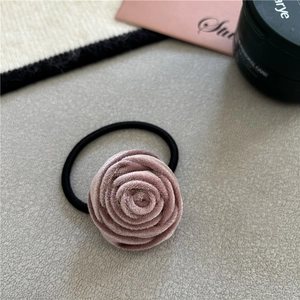 Elegant handmade pink velvet rose hair tie with black elastic band on a stylish background