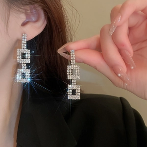 Double-layer geometric silver earrings with full diamonds on a model in a high-fashion style