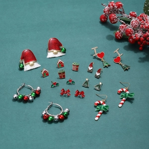 Festive Christmas earring set with enamel Santa hats and candy canes on green background