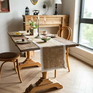 Detailed close-up of natural jute table runner with delicate white lace edges on wood