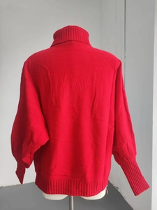 Close-up of red ribbed turtleneck sweater showing warm knitted texture and loose cuffs