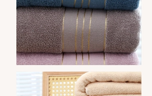 Detailed macro view of soft long-staple cotton bath towels showing looped texture and gold silk borders