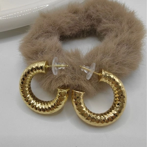 Golden geometric round hoop earrings with diamond-cut texture and silicone backings