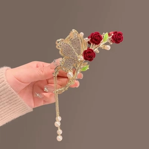 Detail of gold metal hair claw clip with red velvet roses and pearl tassel pendant