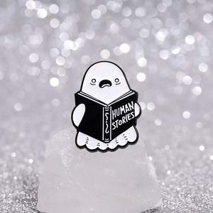 Cute ghost reading Human Stories enamel pin badge accessory on white crystal base