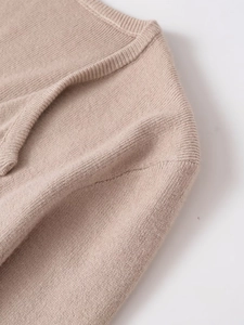 Detail of apricot knit sweater featuring ribbed neckline and fine stitch texture