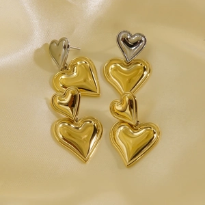 Polished 14K gold and silver layered heart drop earrings on champagne silk background